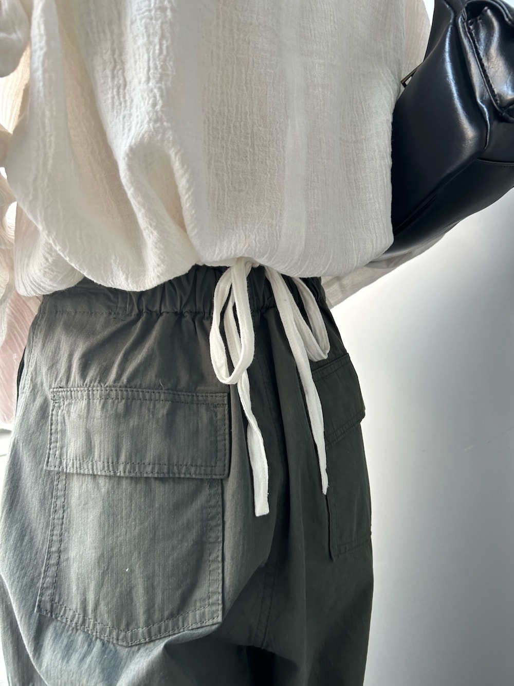 ホワイト系のシャツ/ブラウス、グリーン系のカーゴパンツ、ブラック系のハンドバッグを着用したレディースの夏コーディネートの5枚目の写真