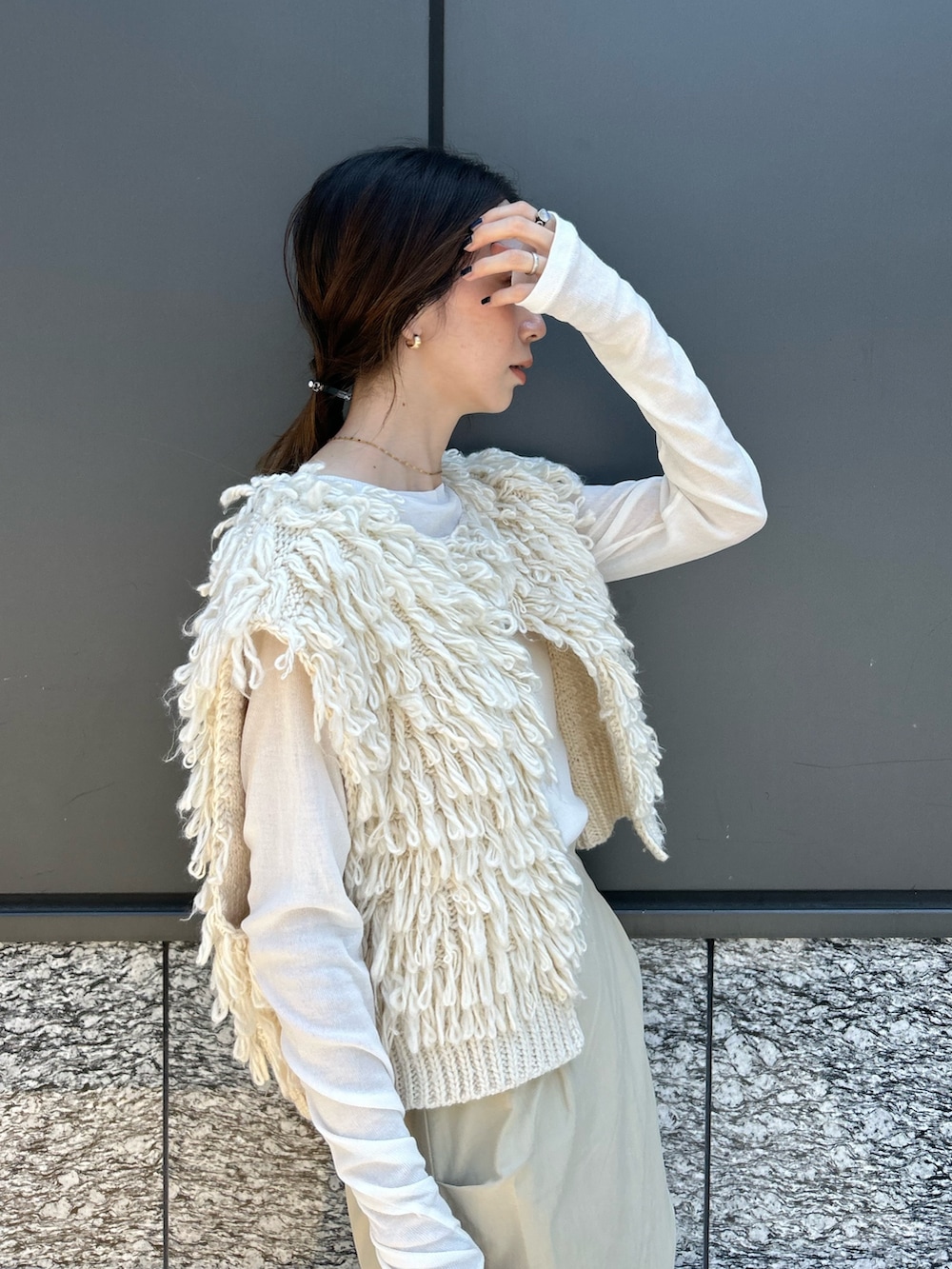 ホワイト系のベスト、ベージュ系のスカート、ブラウン系のブーツを着用したレディースの夏コーディネートの4枚目の写真