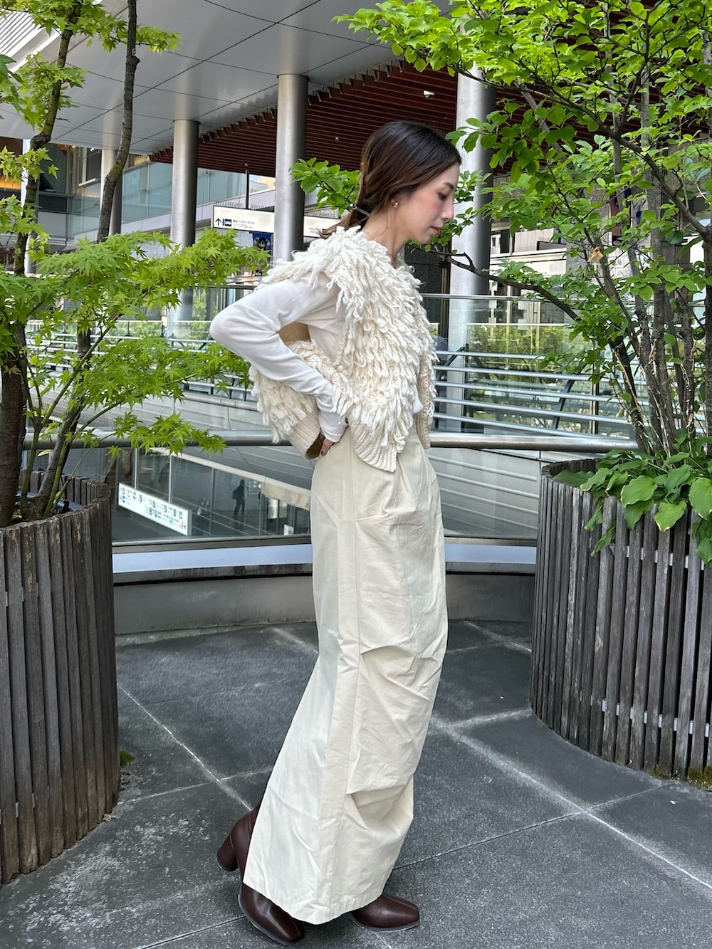 ホワイト系のベスト、ベージュ系のスカート、ブラウン系のブーツを着用したレディースの夏コーディネートの2枚目の写真