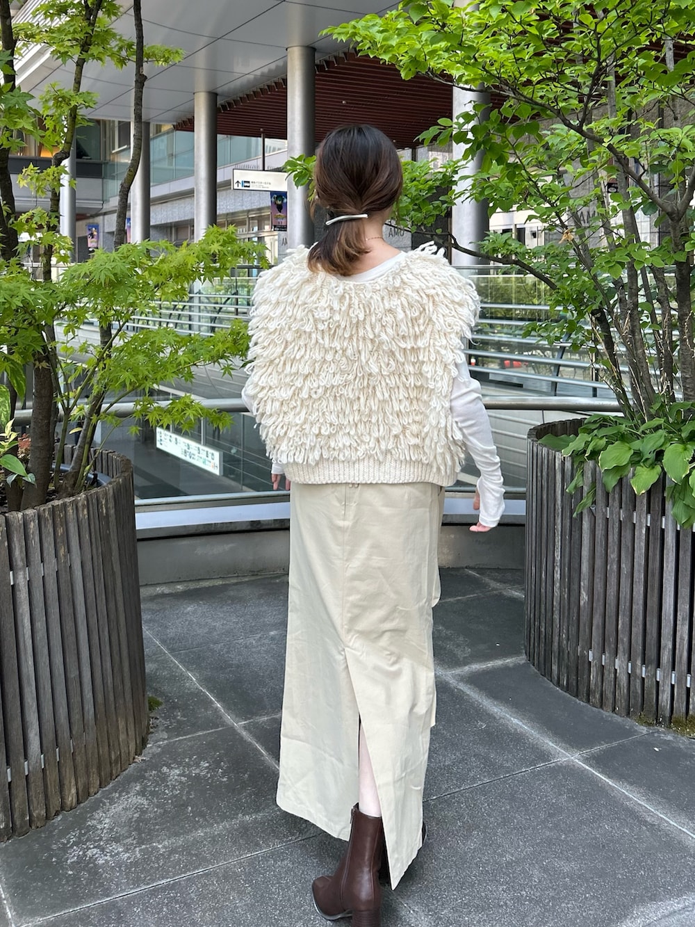 ホワイト系のベスト、ベージュ系のスカート、ブラウン系のブーツを着用したレディースの夏コーディネートの3枚目の写真