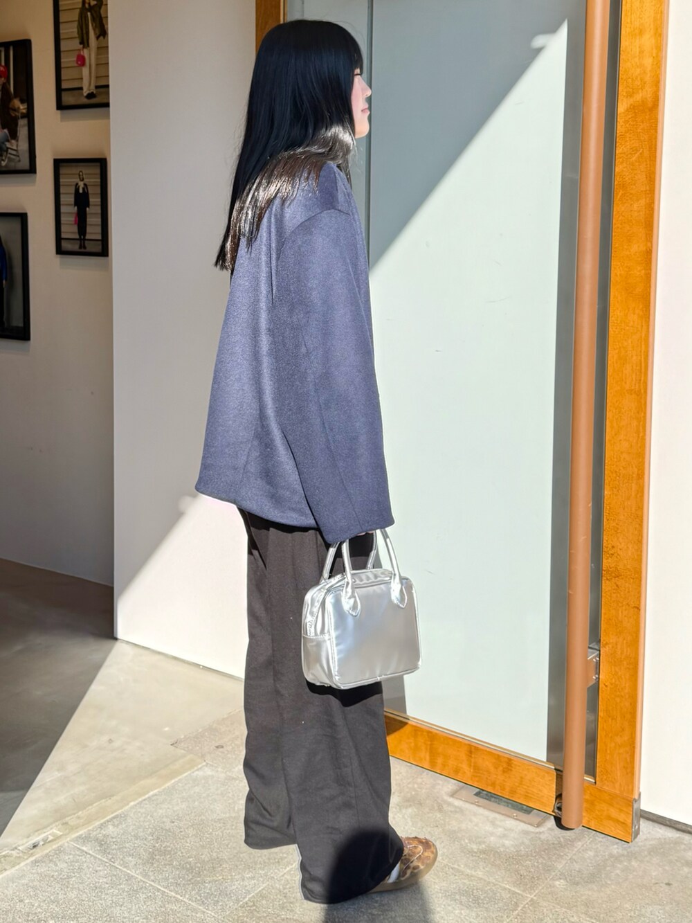 ブルー系のノーカラーコート、ブラック系のその他パンツ、シルバー系のハンドバッグを着用したレディースの冬コーディネートの2枚目の写真