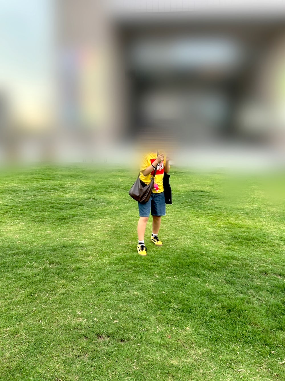 イエロー系のスニーカー、ブルー系のデニムパンツ、ブラウン系のショルダーバッグを着用したレディースの夏コーディネートの2枚目の写真