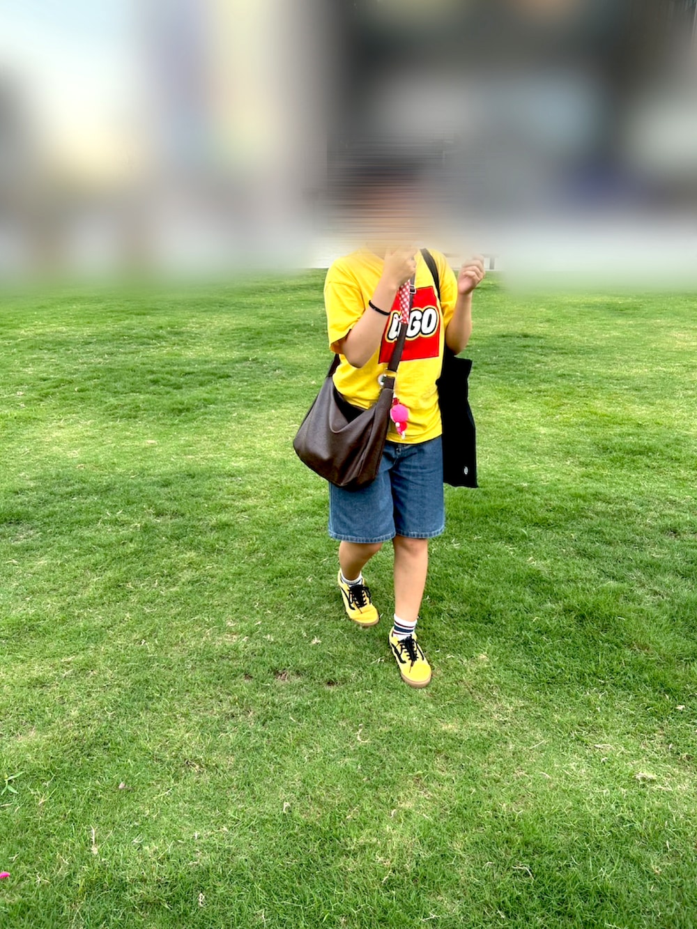 イエロー系のスニーカー、ブルー系のデニムパンツ、ブラウン系のショルダーバッグを着用したレディースの夏コーディネートの3枚目の写真