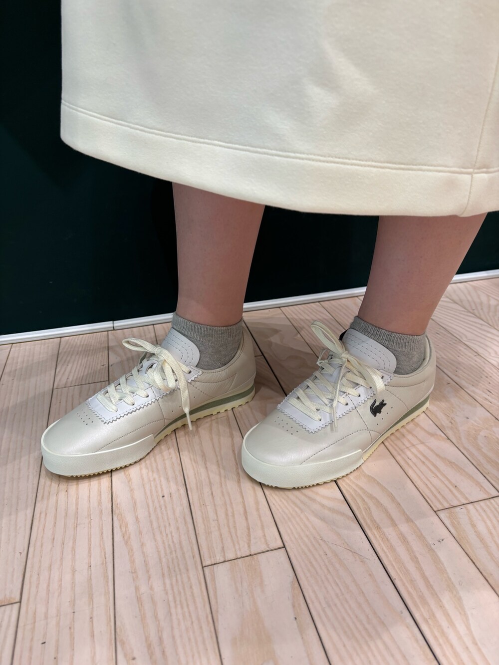 グレー系のブルゾン、ホワイト系のワンピース、ベージュ系のトートバッグを着用したレディースの冬コーディネートの4枚目の写真