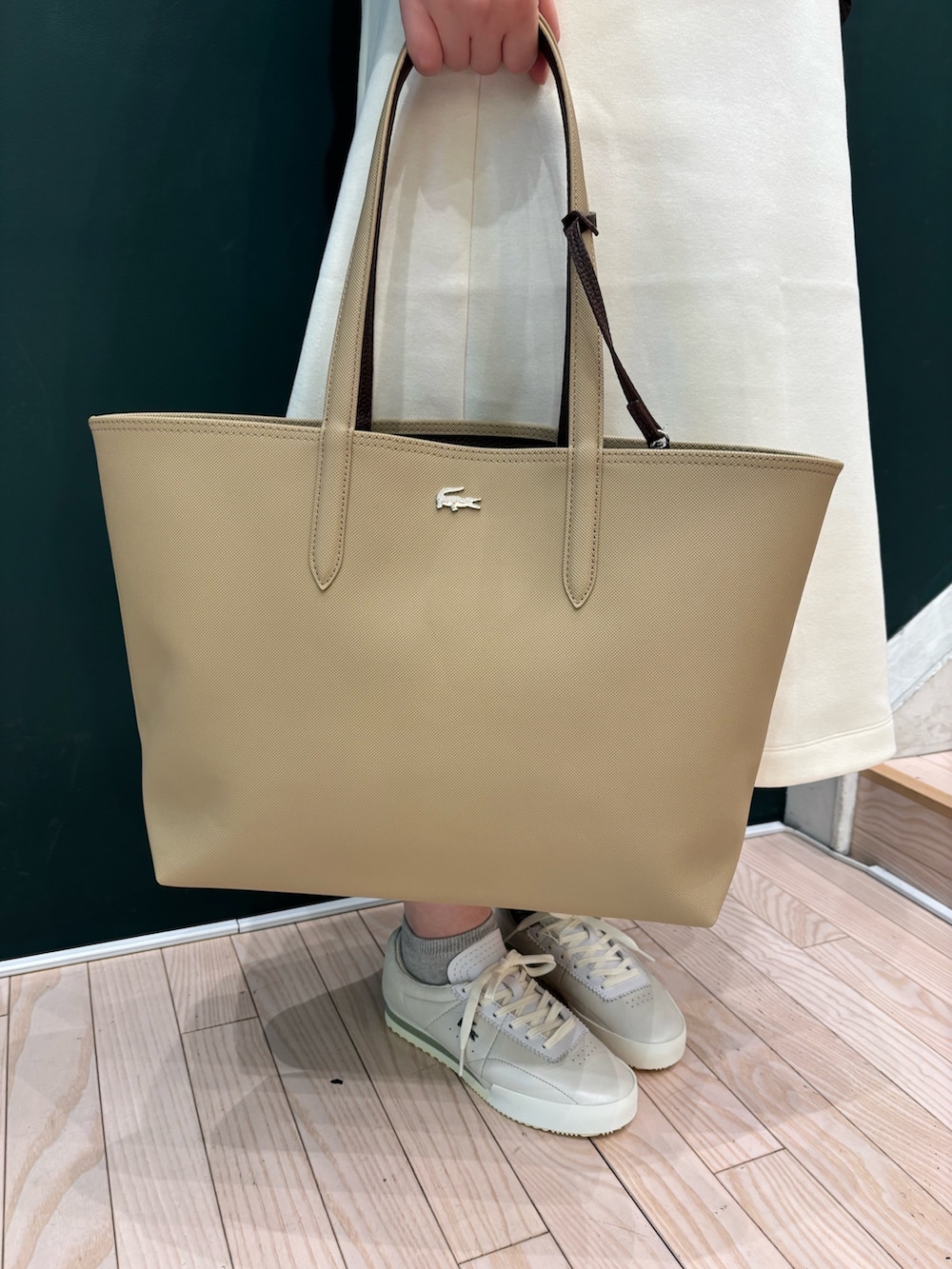 グレー系のブルゾン、ホワイト系のワンピース、ベージュ系のトートバッグを着用したレディースの冬コーディネートの5枚目の写真