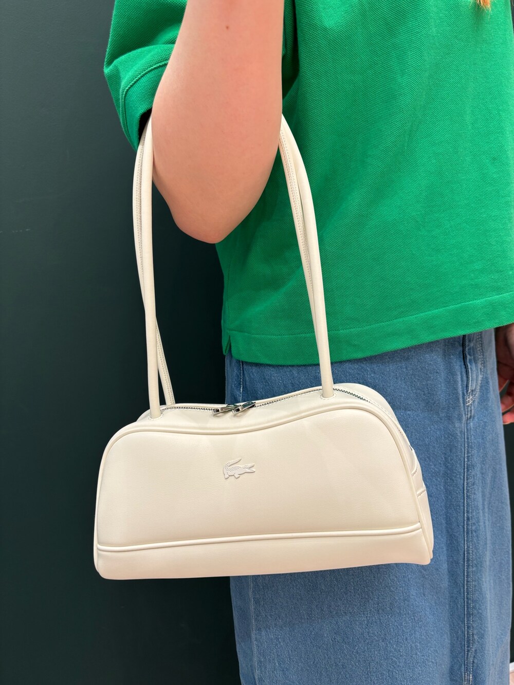 グリーン系のポロシャツ、ブルー系のデニムスカート、ホワイト系のショルダーバッグを着用したレディースの春コーディネートの5枚目の写真