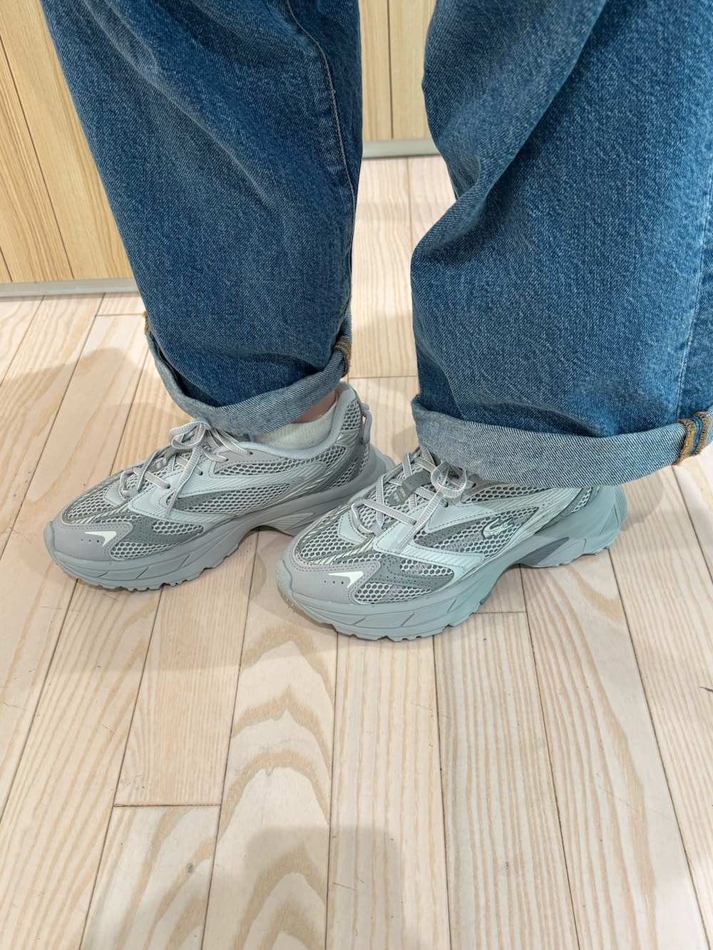 ホワイト系のワンピース、ブルー系のデニムパンツ、グレー系のスニーカーを着用したレディースの夏コーディネートの5枚目の写真