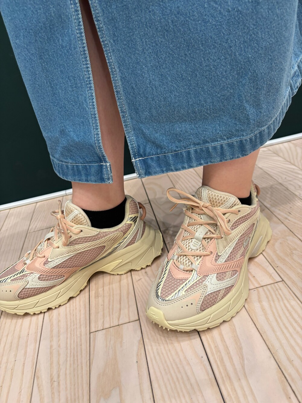 グリーン系のポロシャツ、ブルー系のデニムスカート、ホワイト系のショルダーバッグを着用したレディースの春コーディネートの6枚目の写真