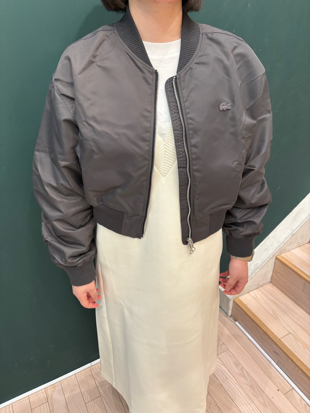 グレー系のブルゾン、ホワイト系のワンピース、ベージュ系のトートバッグを着用したレディースの冬コーディネートの3枚目の写真