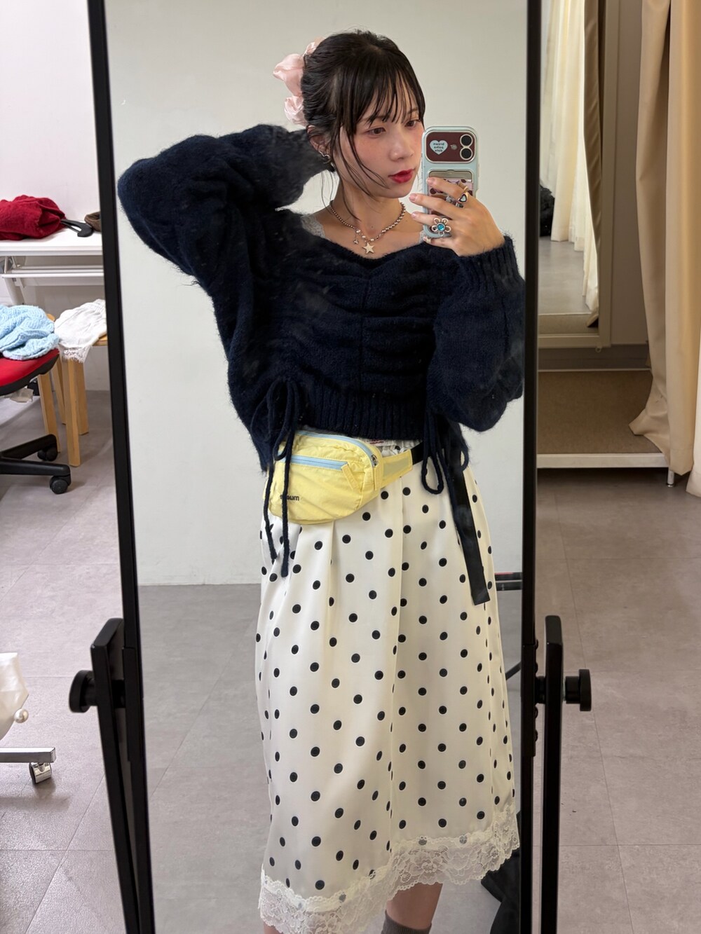 ブルー系のニット/セーター、ホワイト系のスカート、グレー系のスニーカーを着用したレディースの秋コーディネートの2枚目の写真