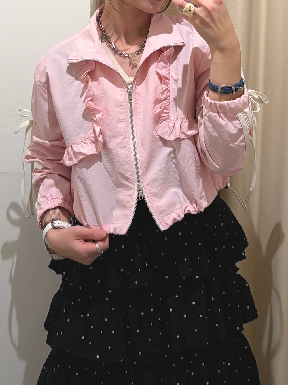 ピンク系のブルゾン、ブラック系のジャンパースカートを着用したレディースの春コーディネートの2枚目の写真