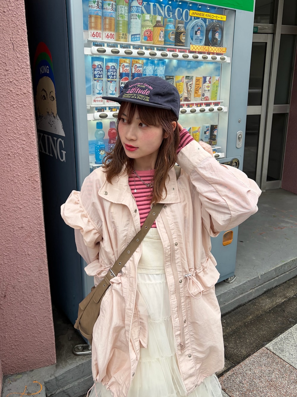 ピンク系のブルゾン、ピンク系のTシャツ/カットソー、ホワイト系のジャンパースカートを着用したレディースの春コーディネートの2枚目の写真