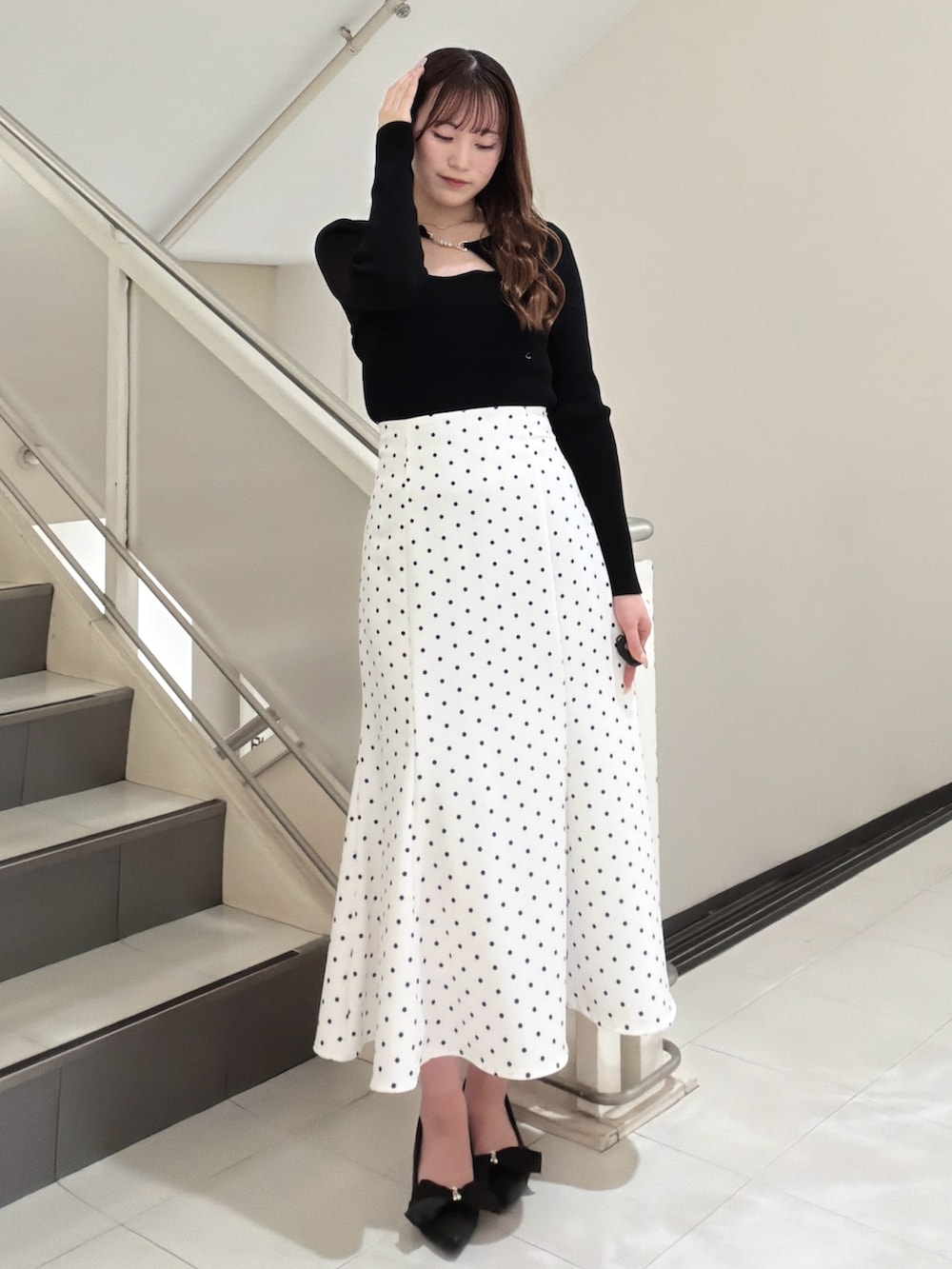 ブラック系のニット/セーター、ホワイト系のスカート、ブラック系のパンプスを着用したレディースの冬コーディネートの2枚目の写真