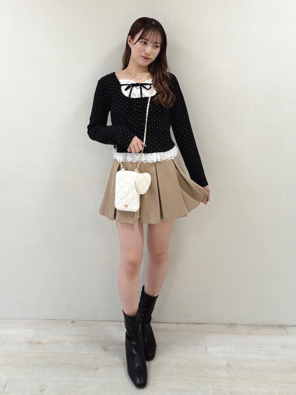 ブラック系のTシャツ/カットソー、ホワイト系のショルダーバッグ、ベージュ系のスカートを着用したレディースの冬コーディネートの2枚目の写真