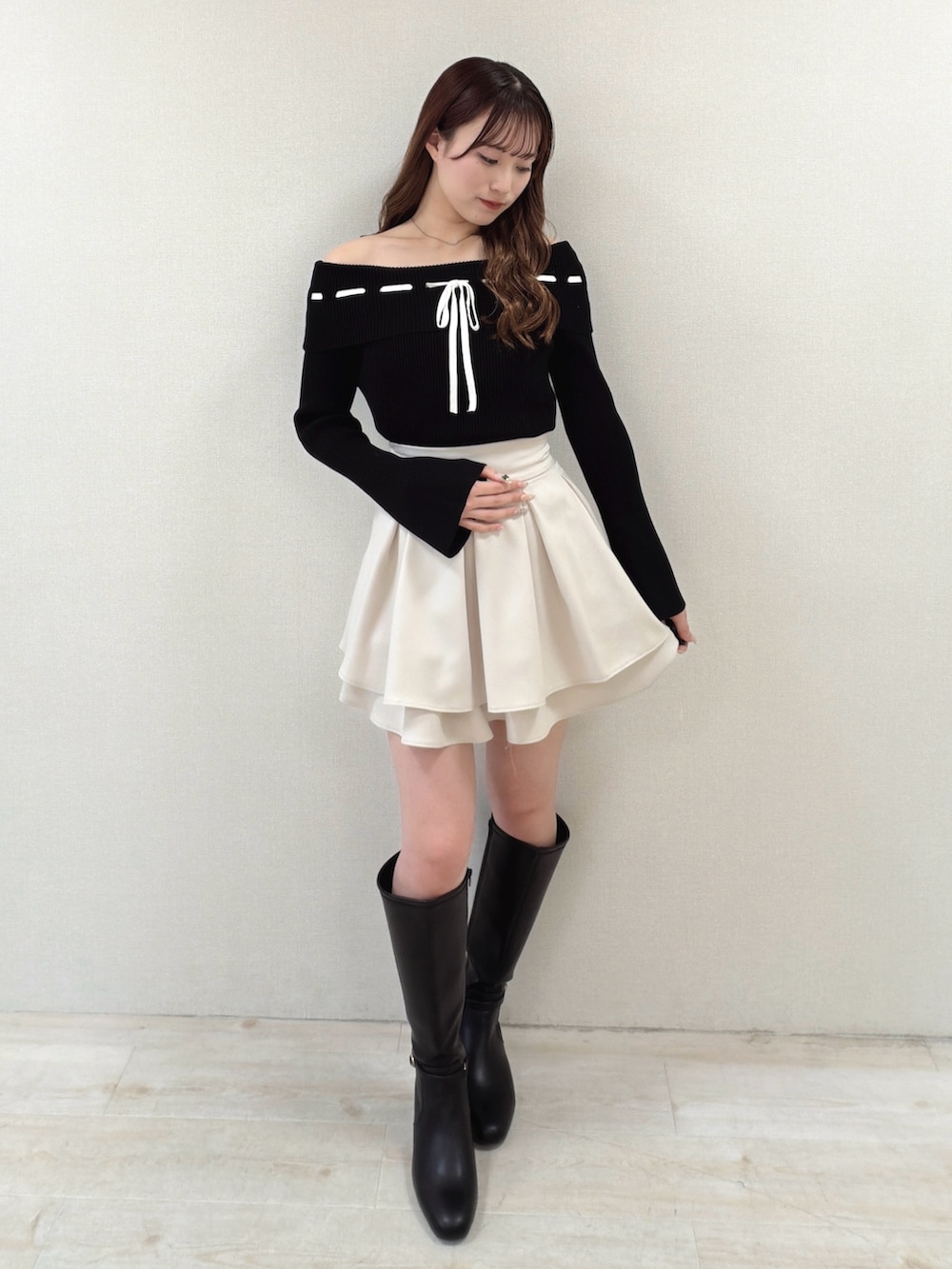 ブラック系のニット/セーター、ベージュ系のスカート、ブラック系のブーツを着用したレディースの冬コーディネートの2枚目の写真