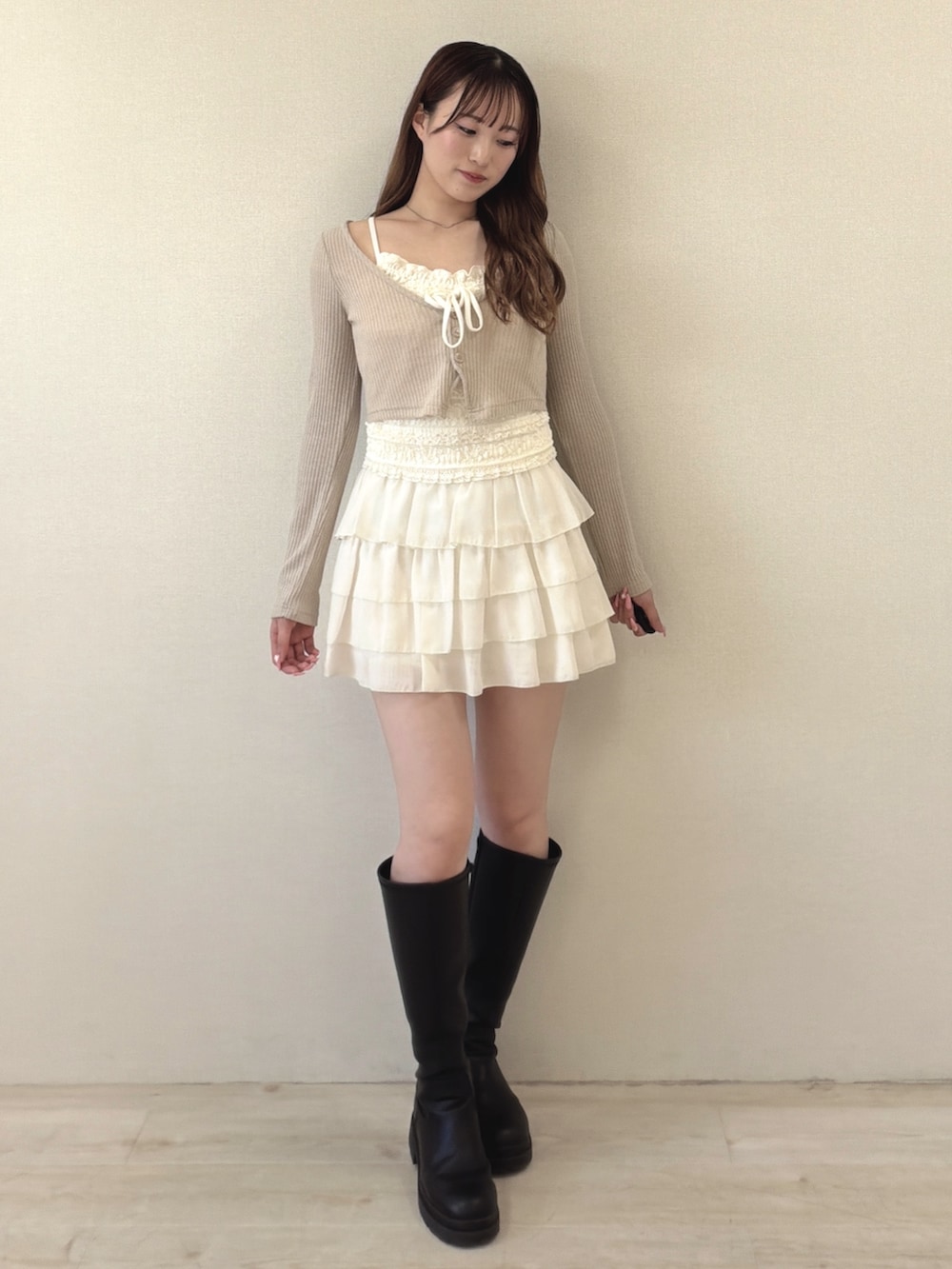 ベージュ系のTシャツ/カットソー、ホワイト系のスカート、ブラック系のブーツを着用したレディースの春コーディネートの2枚目の写真