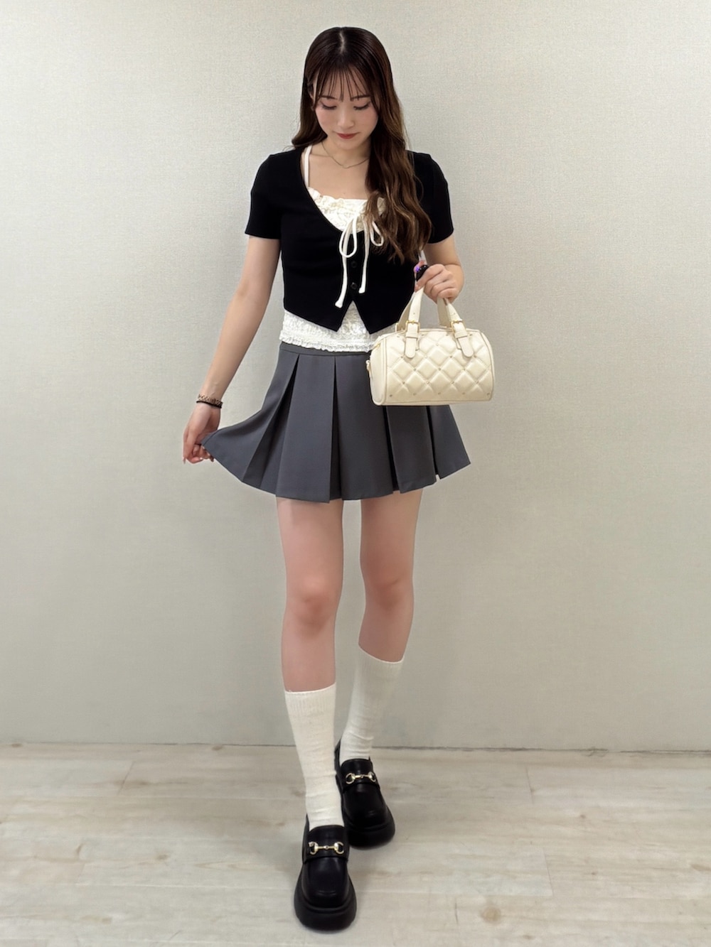 ブラック系のTシャツ/カットソー、グレー系のスカート、ブラック系のパンプスを着用したレディースの春コーディネートの2枚目の写真