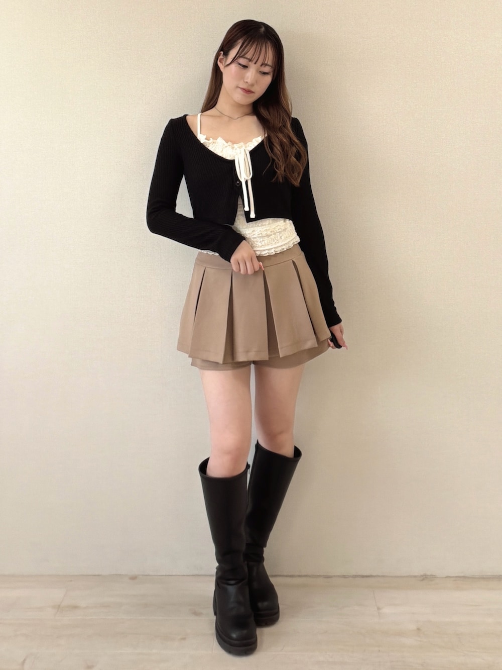 ブラック系のTシャツ/カットソー、ベージュ系のスカート、ブラック系のブーツを着用したレディースの春コーディネートの2枚目の写真