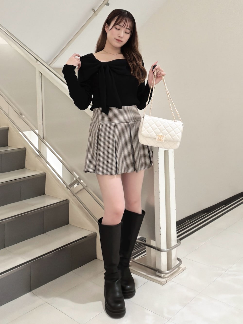 ブラック系のニット/セーター、その他のスカート、ホワイト系のショルダーバッグを着用したレディースの冬コーディネートの2枚目の写真