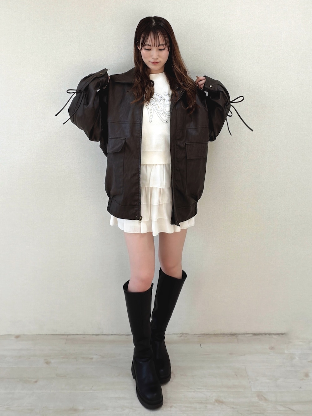 ブラウン系のブルゾン、ホワイト系のニット/セーター、ホワイト系のスカートを着用したレディースの冬コーディネートの2枚目の写真