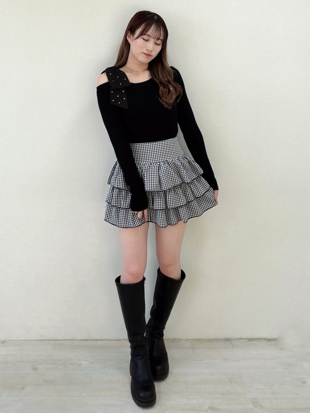 ブラック系のスカート、ブラック系のニット/セーター、ブラック系のブーツを着用したレディースの冬コーディネートの2枚目の写真