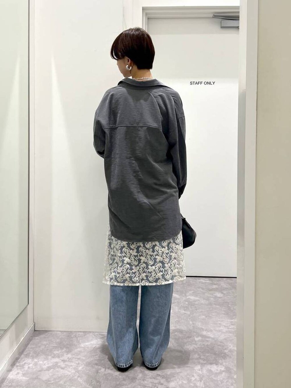 ブラック系のショルダーバッグ、ブルー系のデニムパンツ、ブラック系のシャツ/ブラウスを着用したレディースの秋コーディネートの3枚目の写真