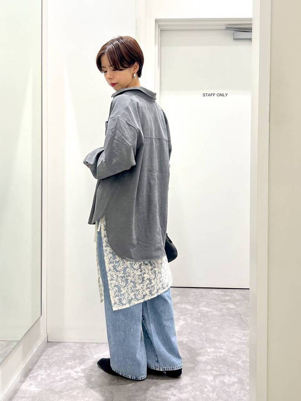 ブラック系のショルダーバッグ、ブルー系のデニムパンツ、ブラック系のシャツ/ブラウスを着用したレディースの秋コーディネートの2枚目の写真