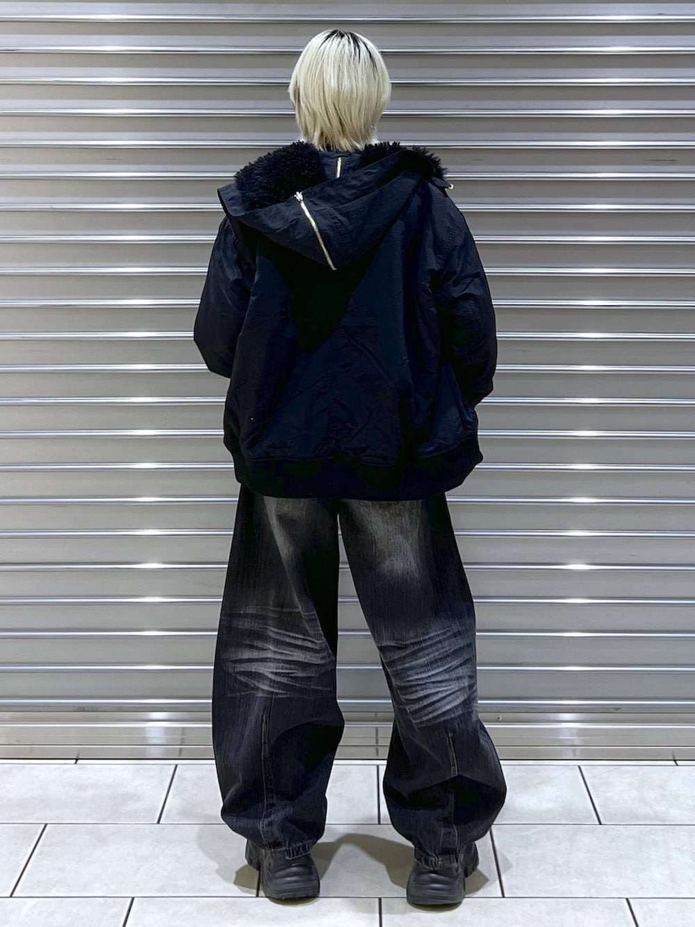 ブラック系のスニーカー、ブラック系のブルゾン、ブラック系のデニムパンツを着用したレディースの秋コーディネートの3枚目の写真