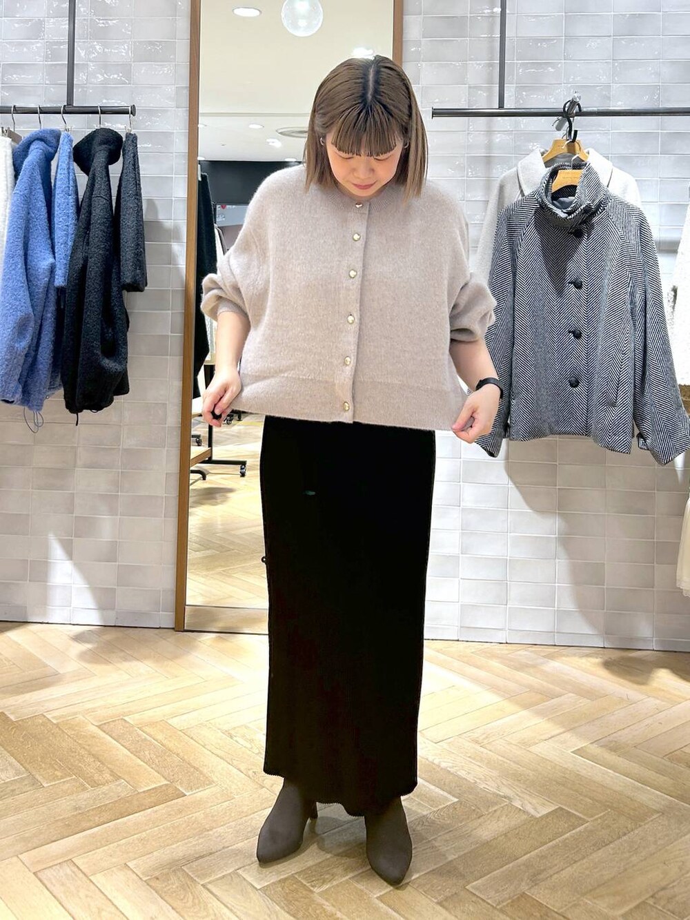 ブラック系のスカート、ベージュ系のカーディガン/ボレロ、ブラウン系のブーツを着用したレディースの秋コーディネートの4枚目の写真