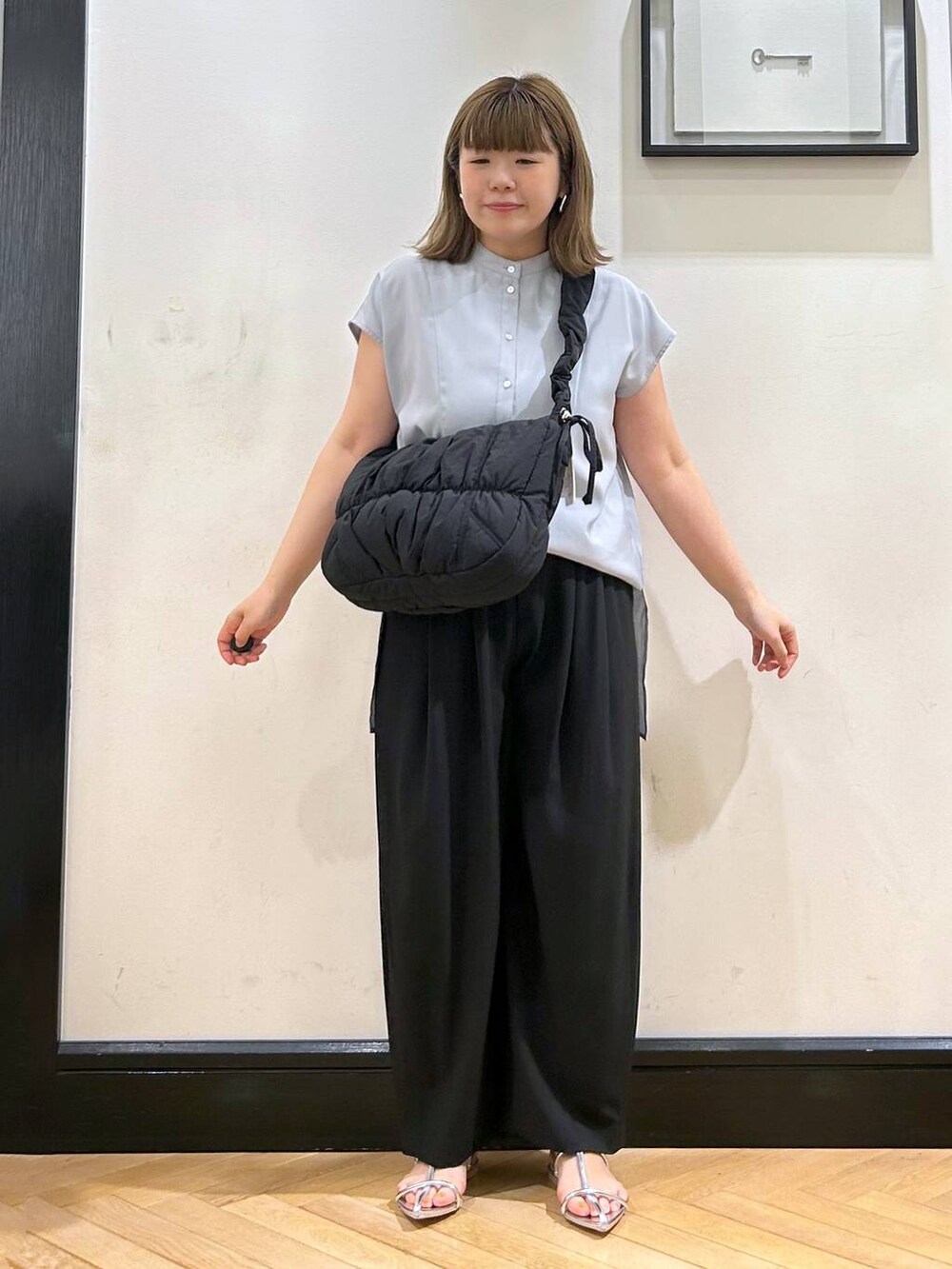 シルバー系のサンダル、ブラック系のスラックス、ブラック系のショルダーバッグを着用したレディースの夏コーディネートの2枚目の写真