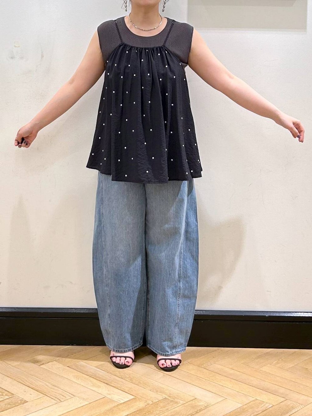 ブルー系のデニムパンツ、ブラウン系のサンダル、グレー系のタンクトップを着用したレディースの夏コーディネートの9枚目の写真