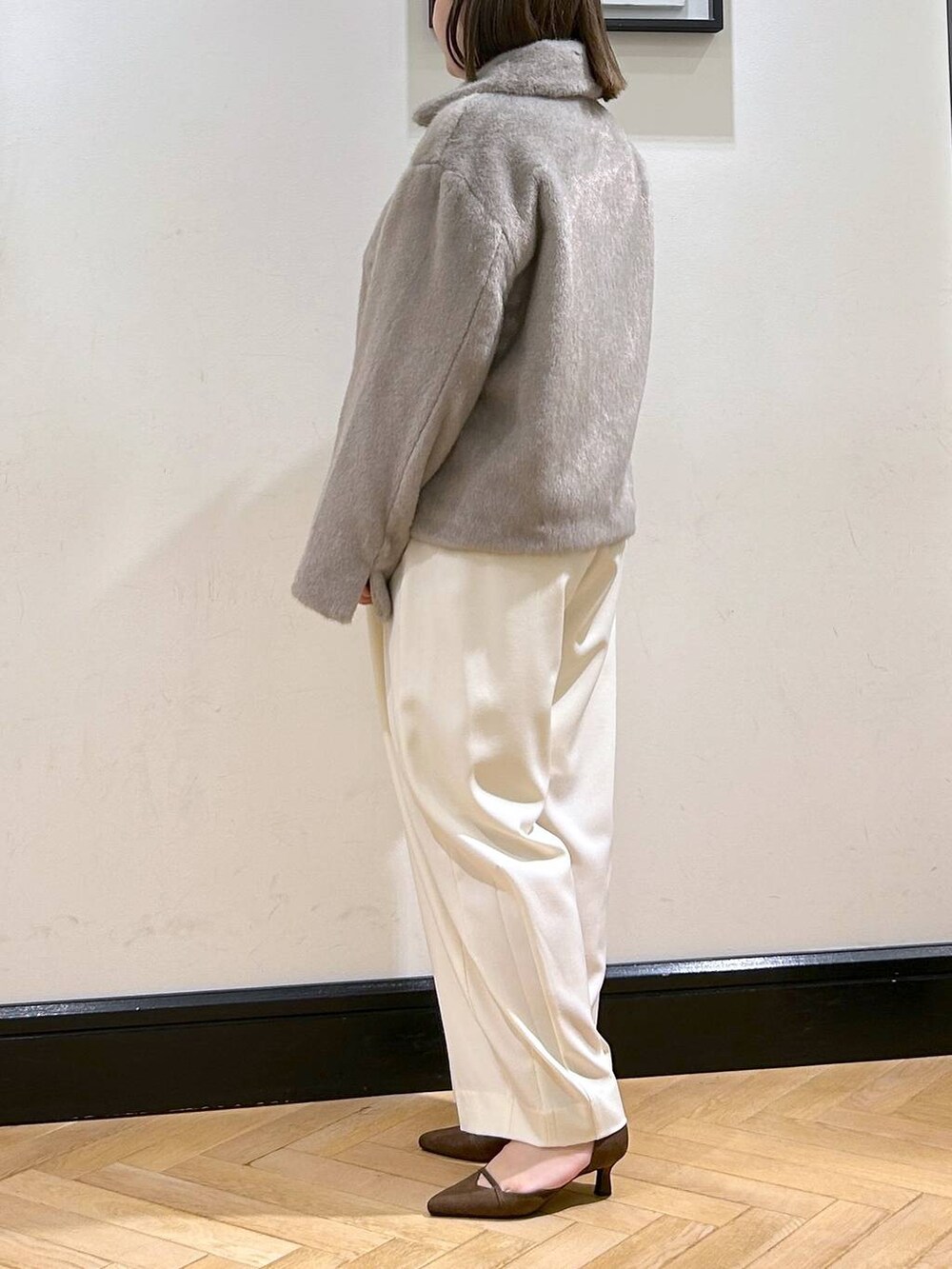 ホワイト系のスラックス、グレー系のその他アウター、ゴールド系のネックレスを着用したレディースの秋コーディネートの5枚目の写真