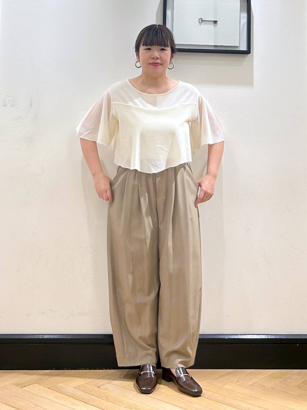 ベージュ系のスラックス、ブラウン系のローファー、ホワイト系のニット/セーターを着用したレディースの夏コーディネートの4枚目の写真