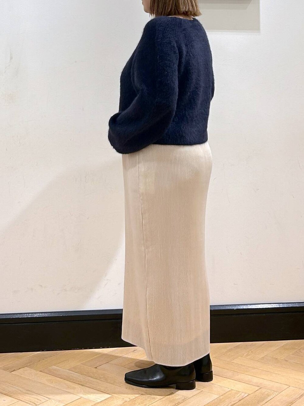 ブルー系のニット/セーター、ホワイト系のスカート、ブラック系のブーツを着用したレディースの秋コーディネートの7枚目の写真