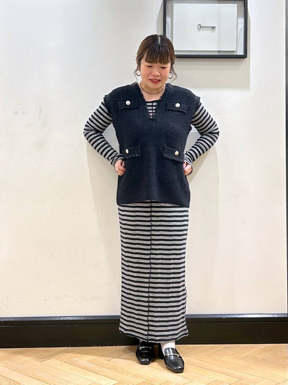 ブルー系のベスト、ブラック系のローファー、ベージュ系のショルダーバッグを着用したレディースの秋コーディネートの2枚目の写真