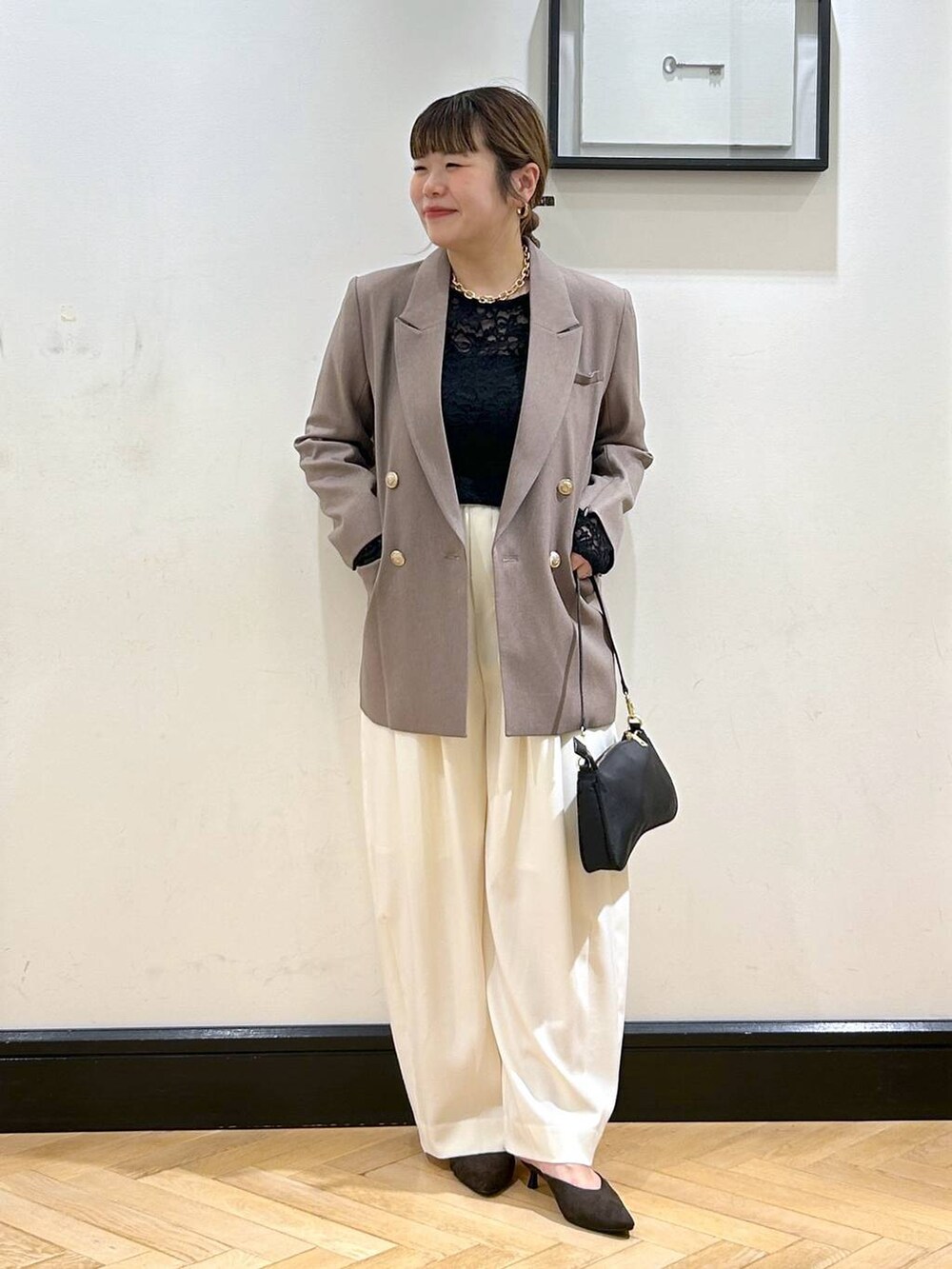 ホワイト系のスラックス、ブラウン系のパンプス、ブラック系のショルダーバッグを着用したレディースの秋コーディネートの4枚目の写真