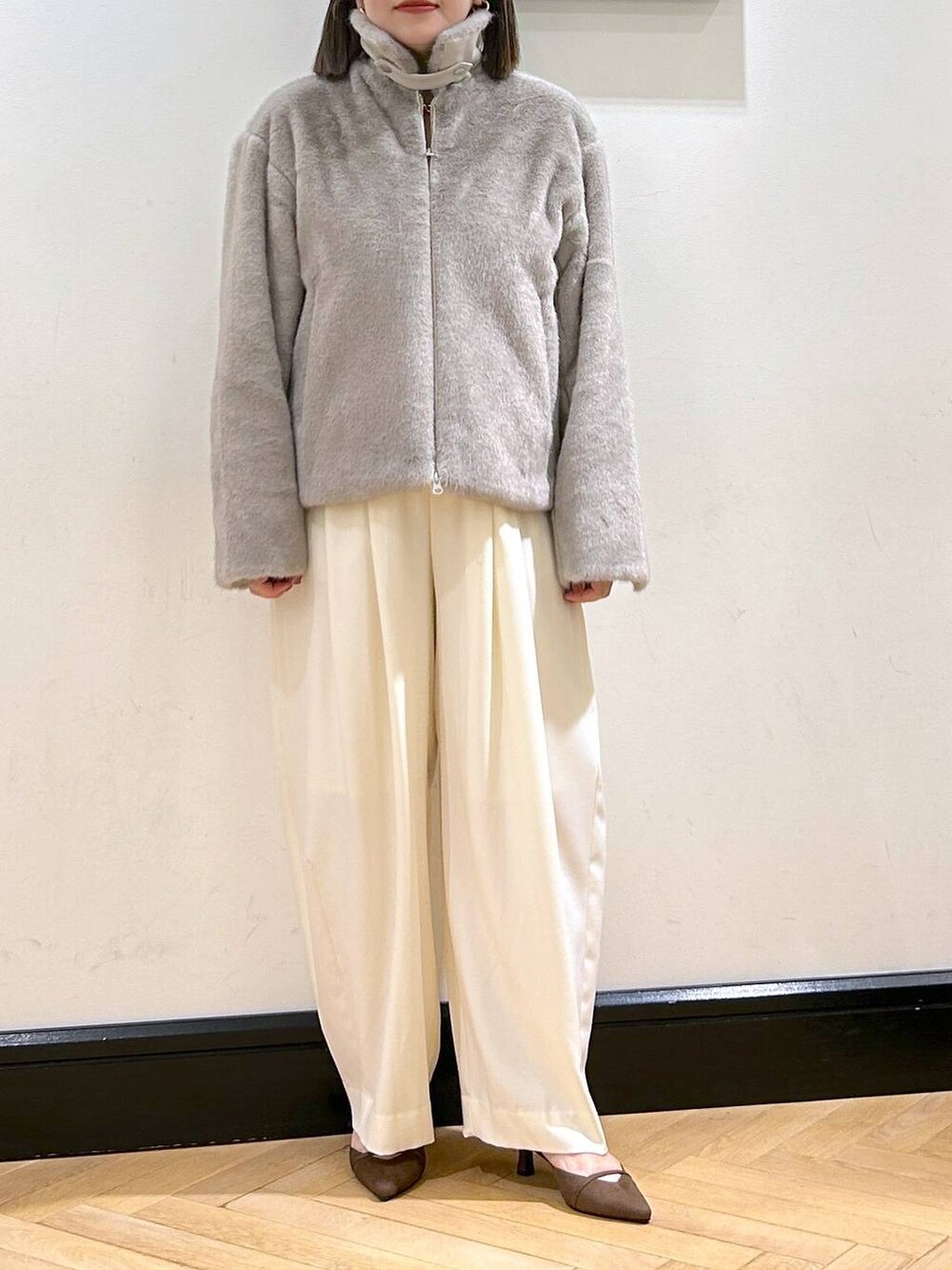 ホワイト系のスラックス、グレー系のその他アウター、ゴールド系のネックレスを着用したレディースの秋コーディネートの7枚目の写真