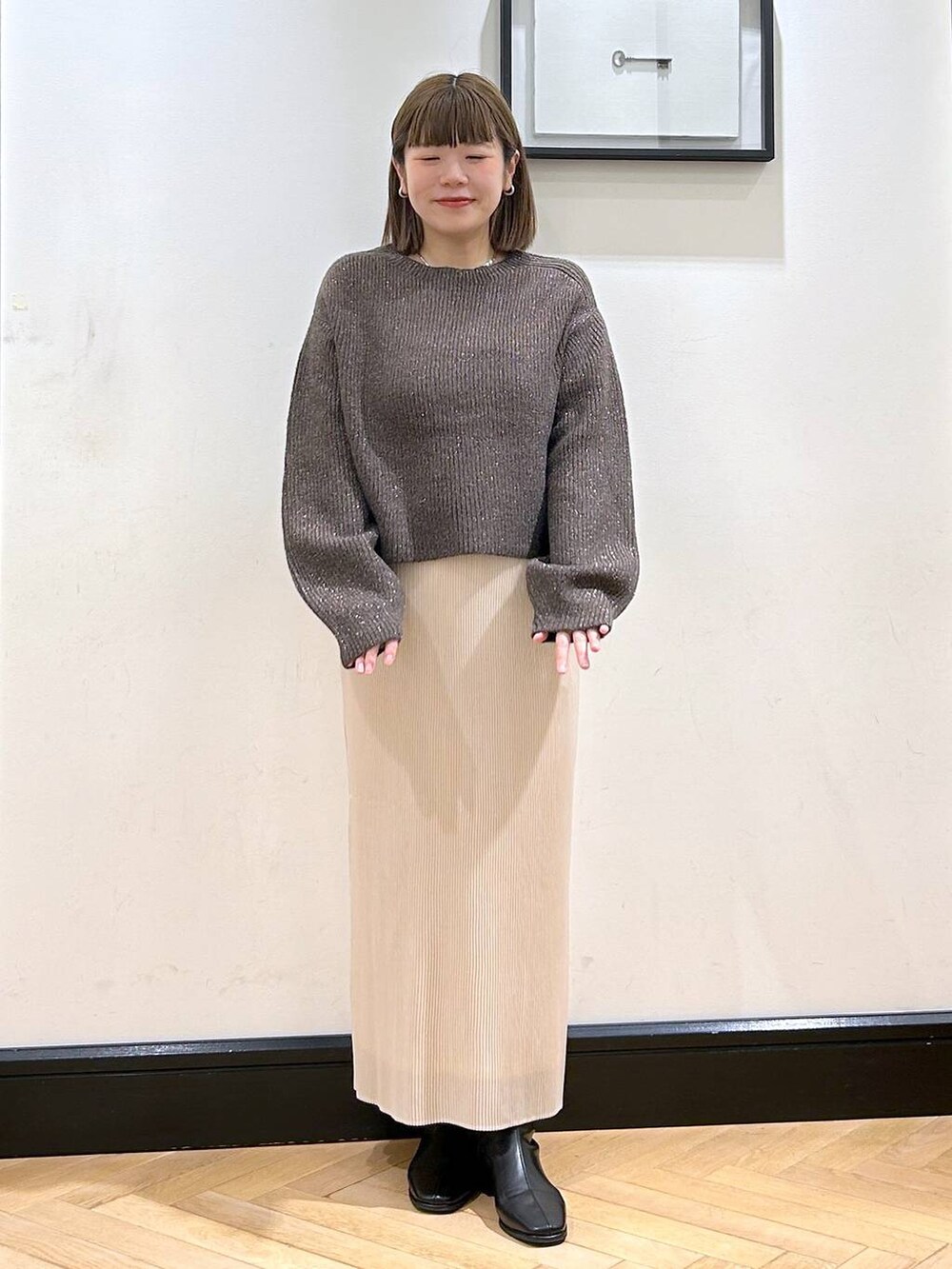 ブラウン系のニット/セーター、ホワイト系のスカート、ブラック系のブーツを着用したレディースの秋コーディネートの5枚目の写真