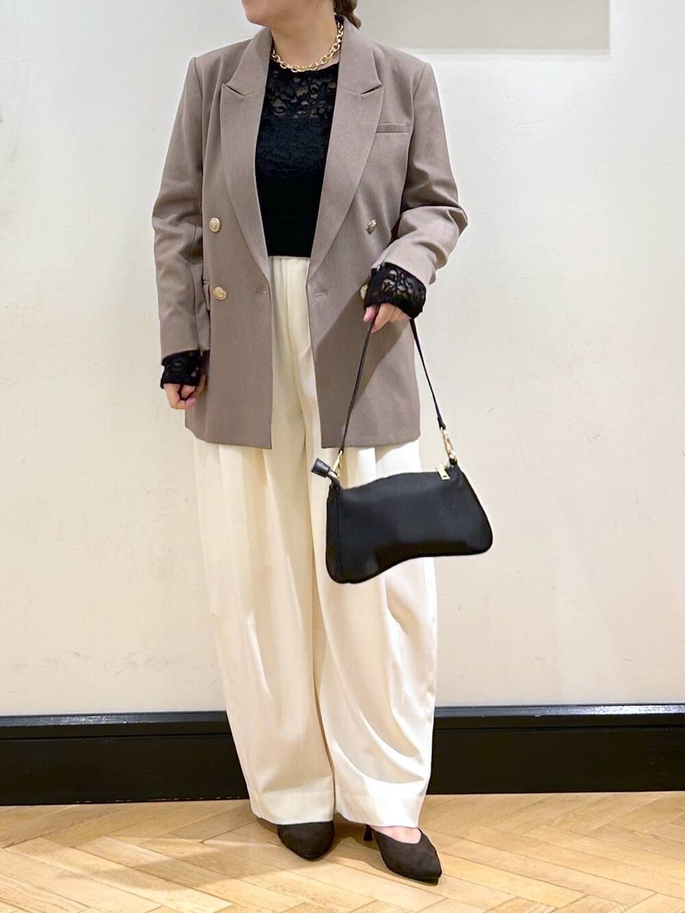 ホワイト系のスラックス、ブラウン系のパンプス、ブラック系のショルダーバッグを着用したレディースの秋コーディネートの9枚目の写真