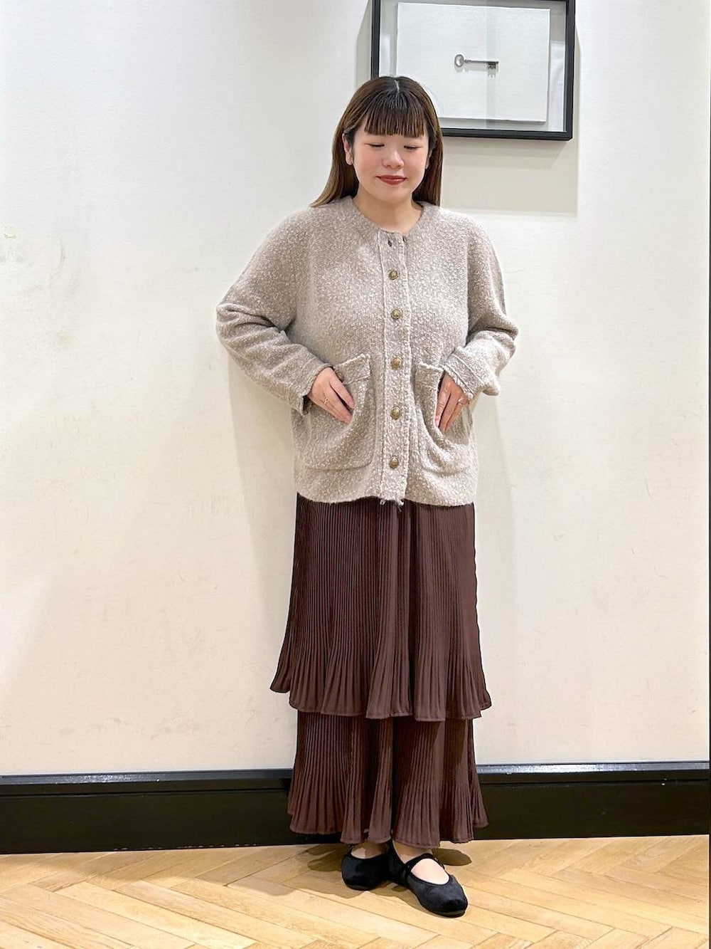 ブラウン系のスカート、ベージュ系のカーディガン/ボレロ、ブラック系のバレエシューズを着用したレディースの秋コーディネートの5枚目の写真