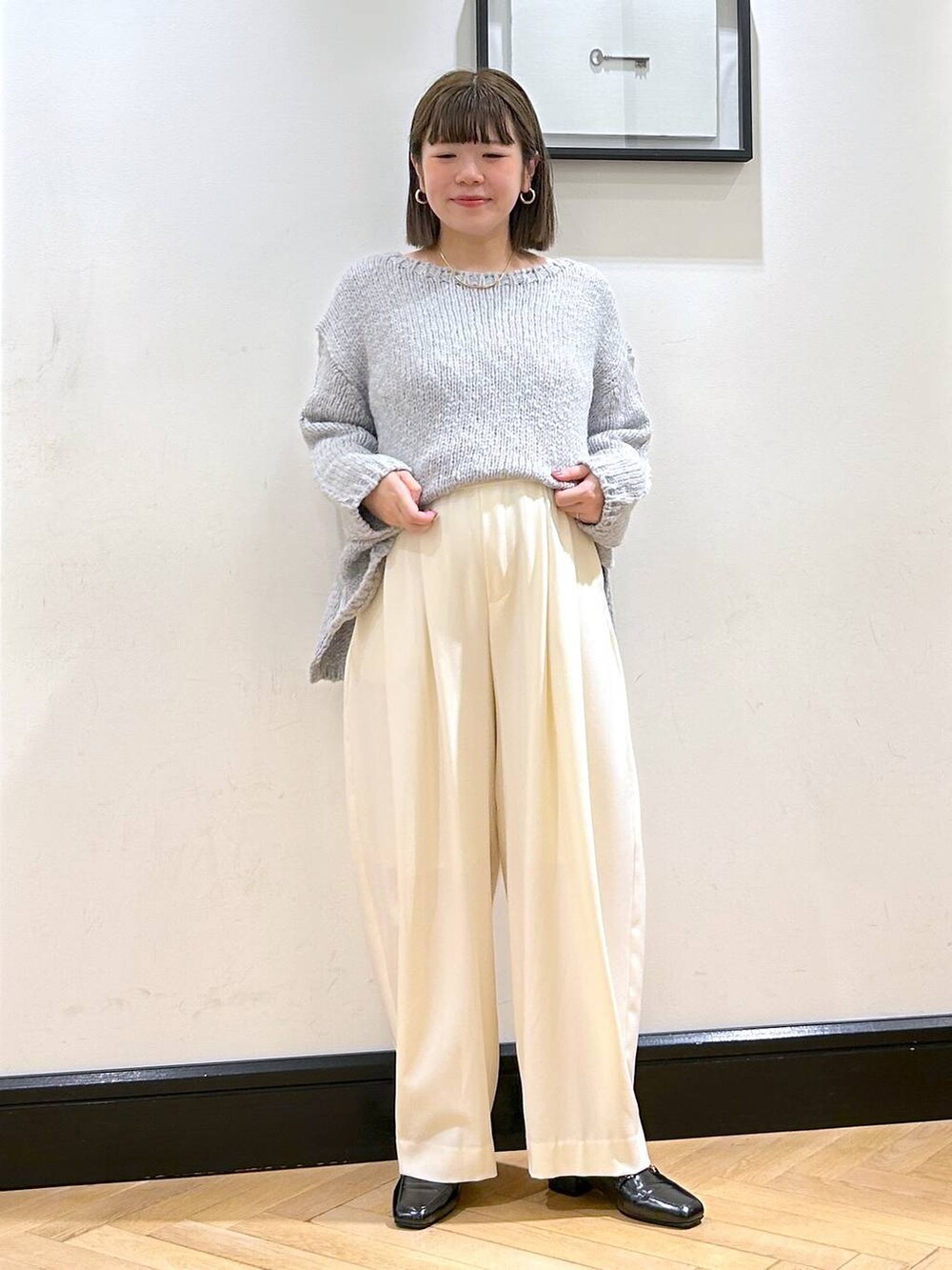 ホワイト系のスラックス、ブラック系のローファー、グレー系のニット/セーターを着用したレディースの秋コーディネートの2枚目の写真