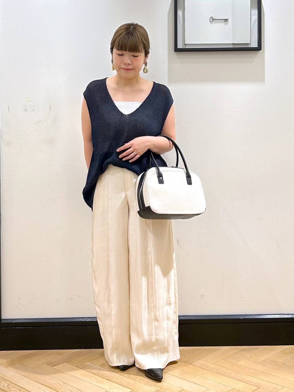 ブラック系のパンプス、ホワイト系のタンクトップ、ブラック系のボストンバッグを着用したレディースの夏コーディネートの3枚目の写真