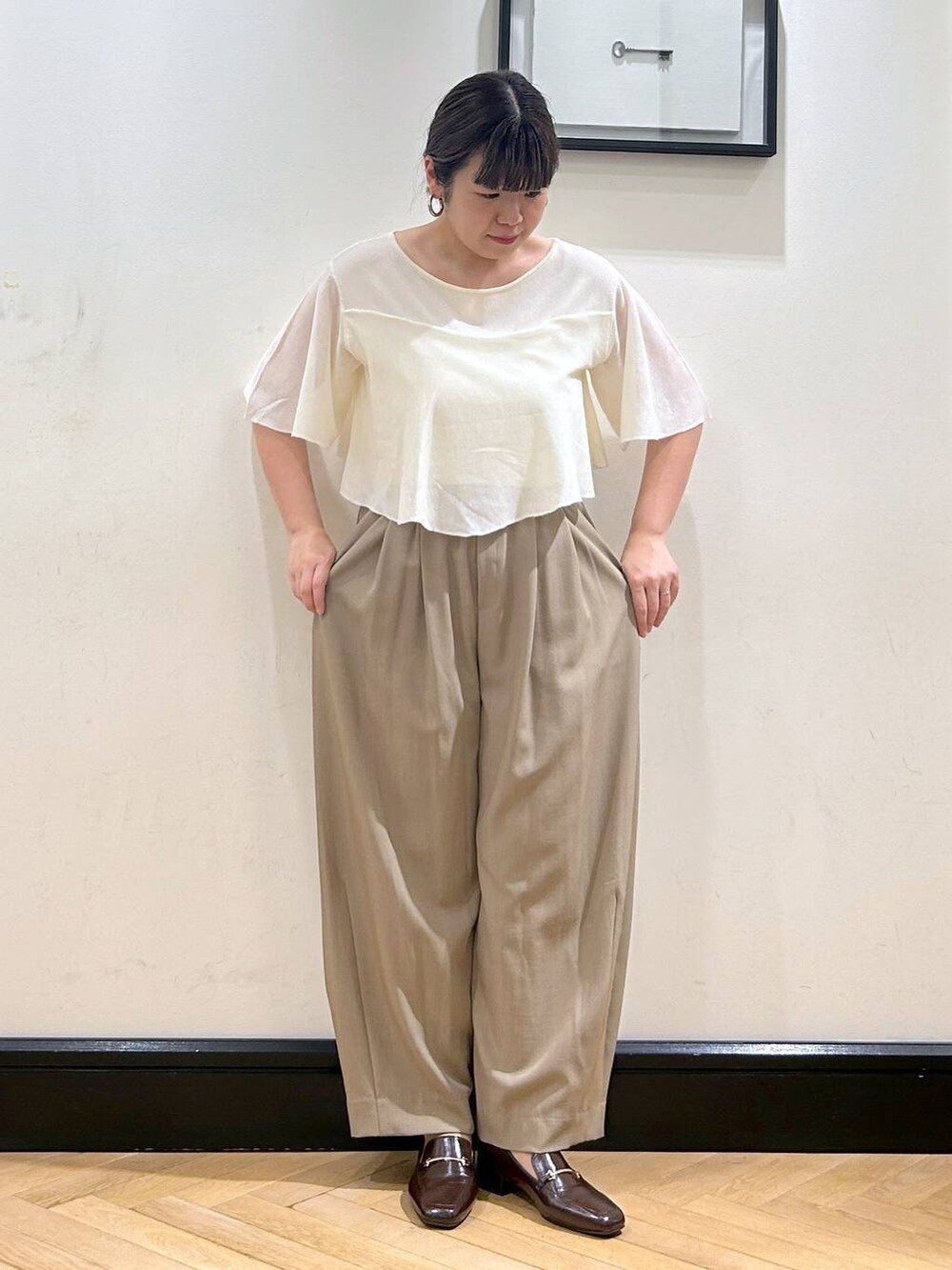 ベージュ系のスラックス、ブラウン系のローファー、ホワイト系のニット/セーターを着用したレディースの夏コーディネートの5枚目の写真