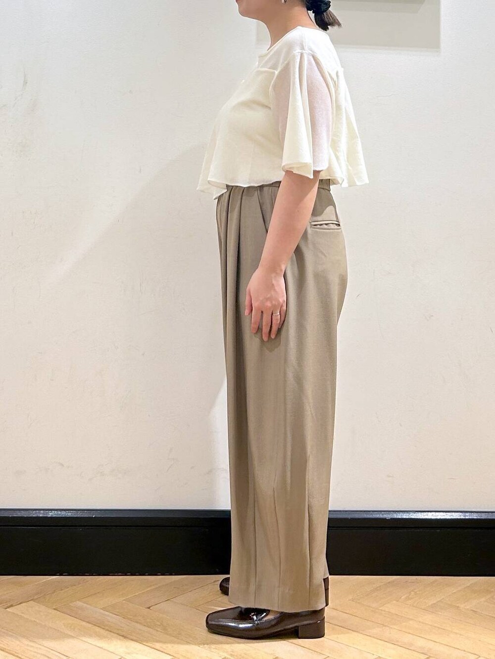 ベージュ系のスラックス、ブラウン系のローファー、ホワイト系のニット/セーターを着用したレディースの夏コーディネートの8枚目の写真