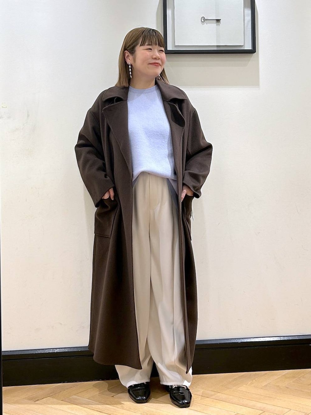 ブラウン系のステンカラーコート、ブラック系のローファー、ブルー系のニット/セーターを着用したレディースの秋コーディネートの4枚目の写真