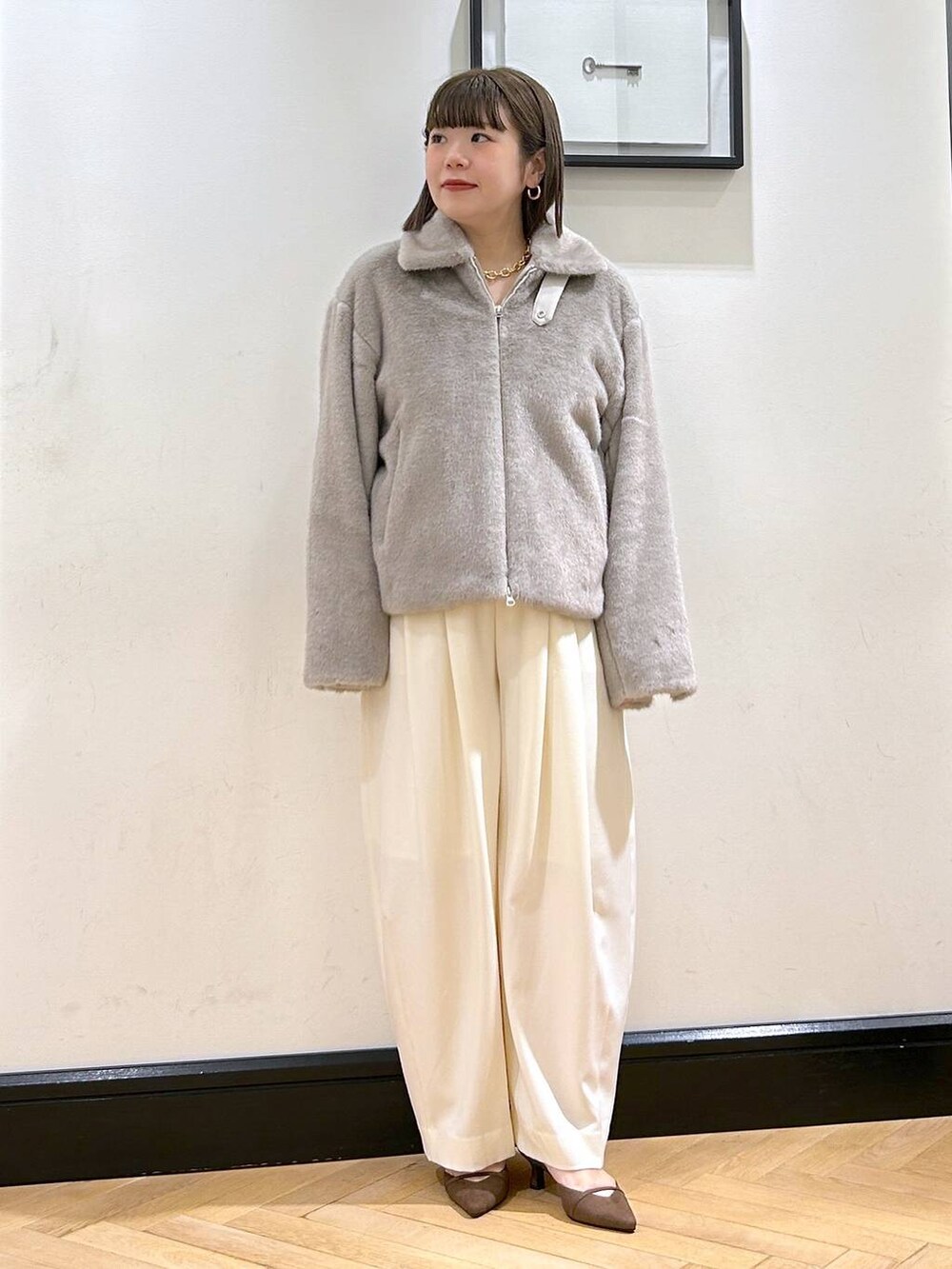 ホワイト系のスラックス、グレー系のその他アウター、ゴールド系のネックレスを着用したレディースの秋コーディネートの4枚目の写真
