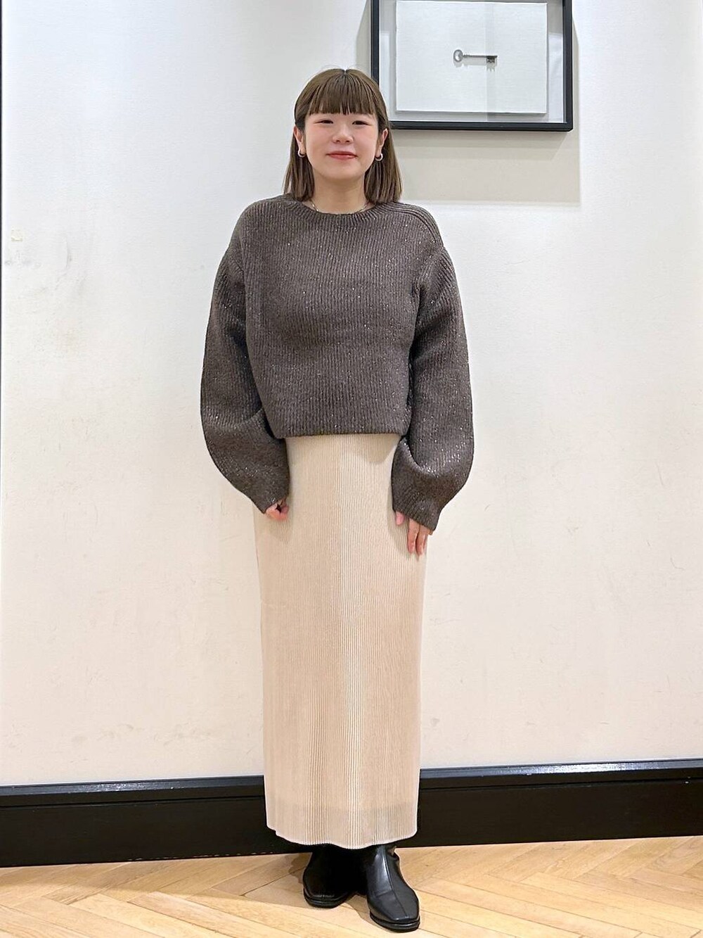 ブラウン系のニット/セーター、ホワイト系のスカート、ブラック系のブーツを着用したレディースの秋コーディネートの4枚目の写真