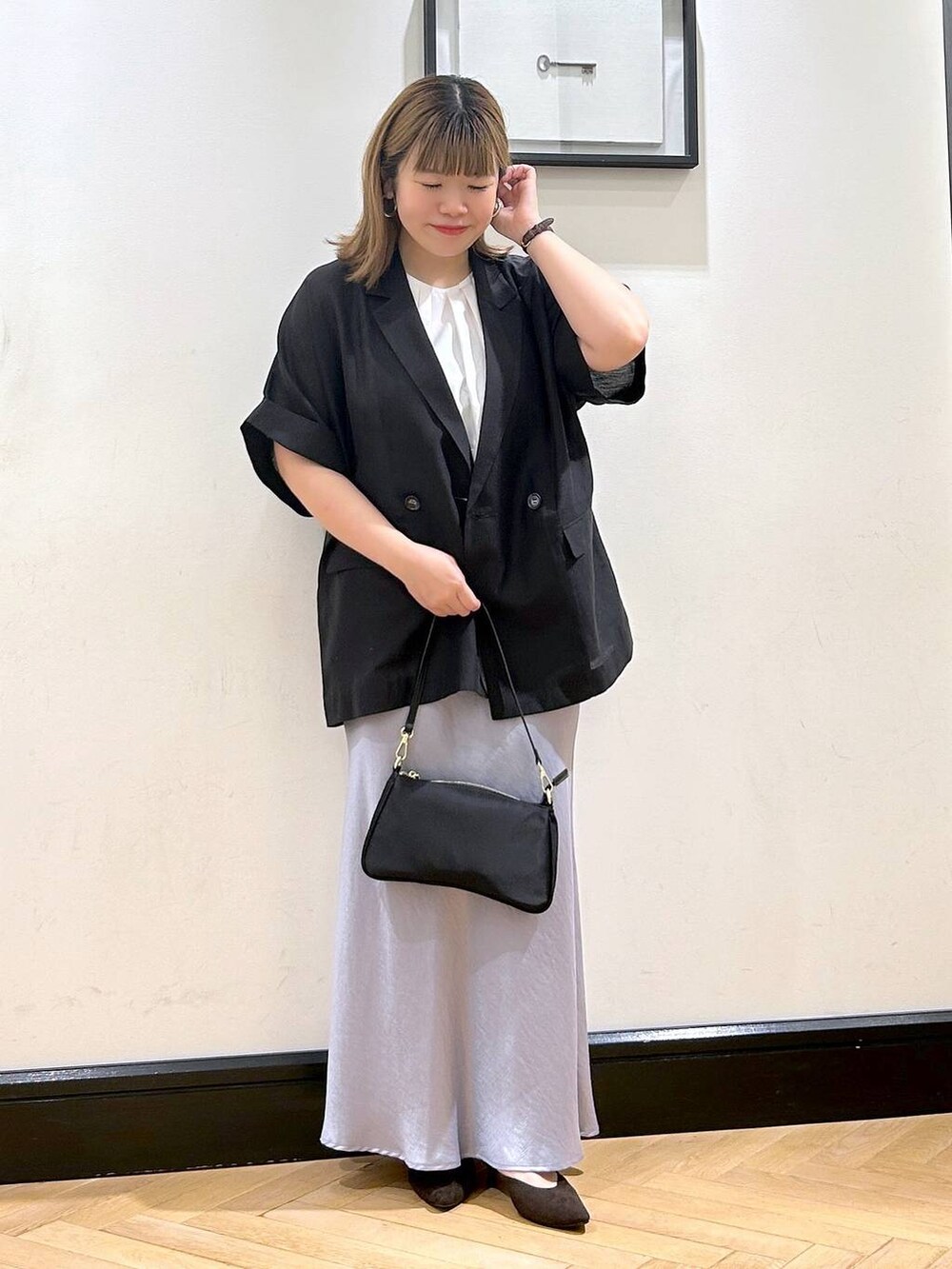 ブルー系のスカート、ブラウン系のパンプス、ホワイト系のシャツ/ブラウスを着用したレディースの夏コーディネートの2枚目の写真
