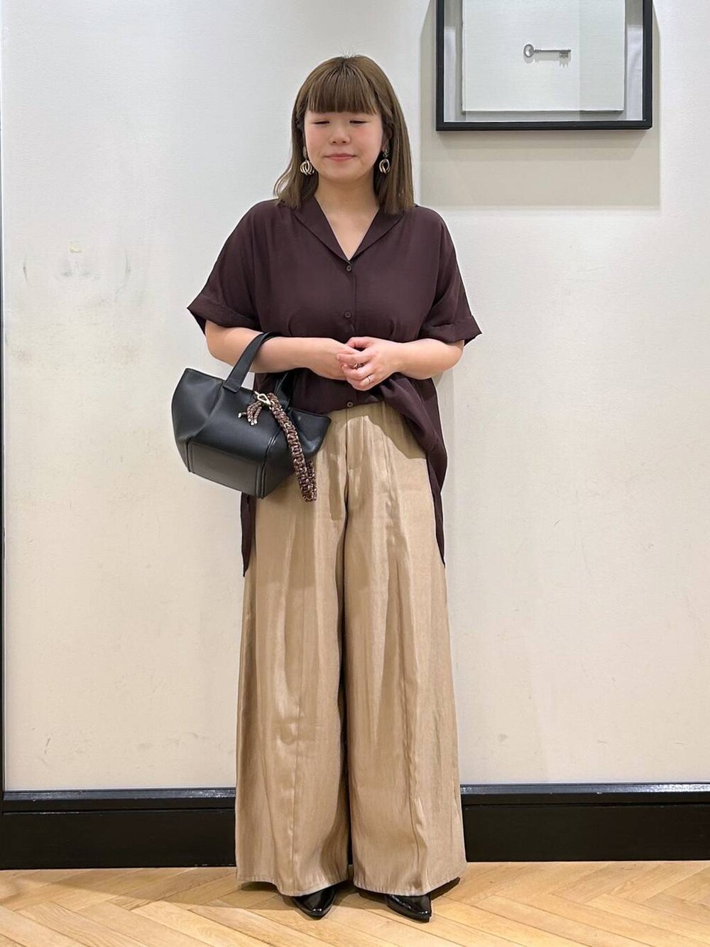 ブラウン系のシャツ/ブラウス、ブラック系のパンプス、ブラック系のハンドバッグを着用したレディースの夏コーディネートの2枚目の写真