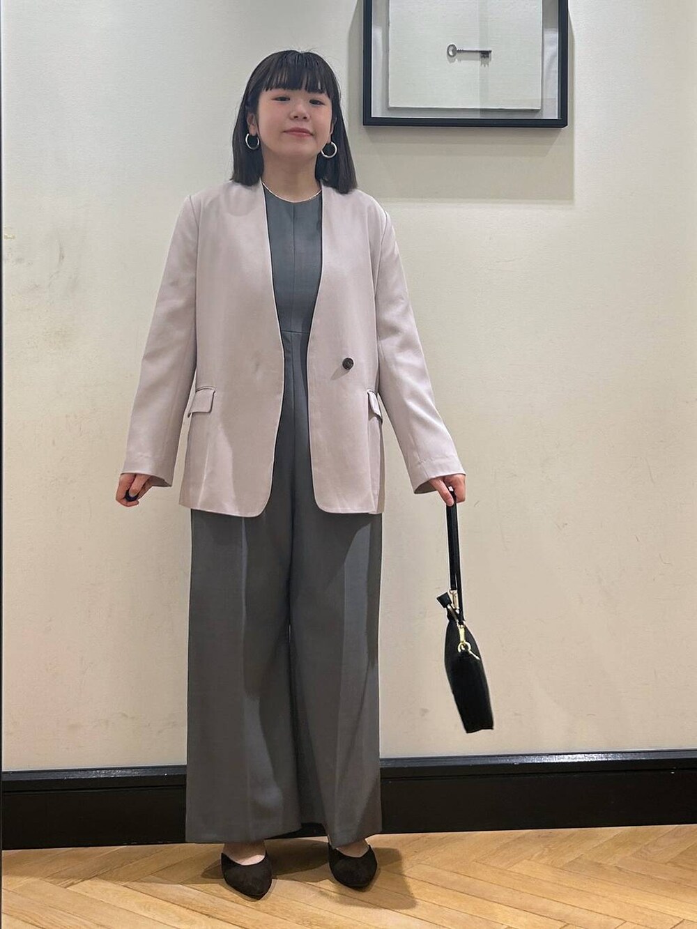 ブラウン系のパンプス、グレー系のノーカラージャケット、ブラック系のショルダーバッグを着用したレディースの夏コーディネートの3枚目の写真